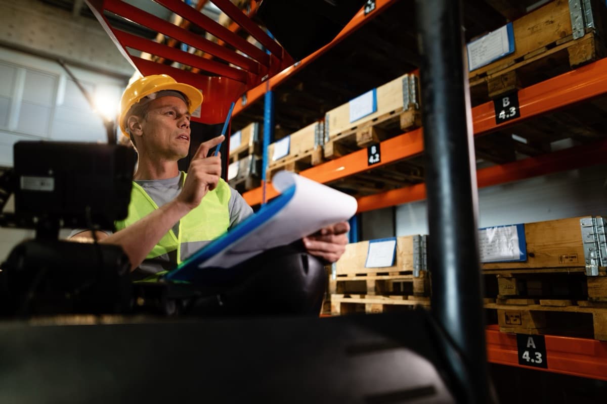 Trabajador revisando inventario con una pauta en un centro de distribución